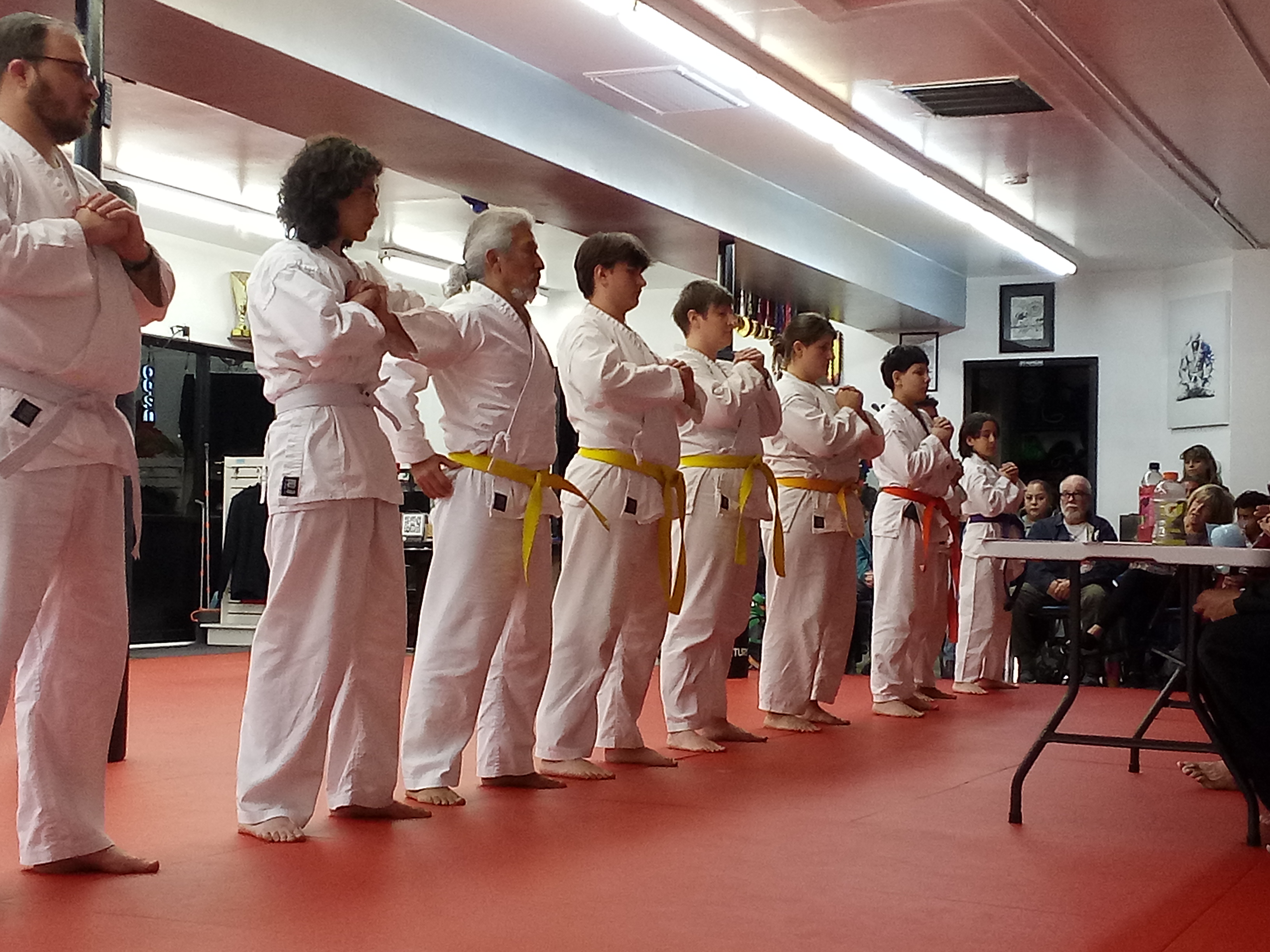 Students lined up in white gis on the red mat during a ceremony at Rhyno's PKKA